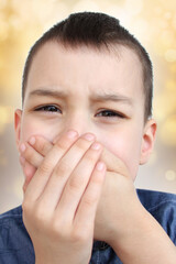 kid, a schoolboy holds his mouth with two hands, wrinkles from toothache, the concept of pediatric...