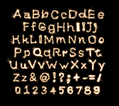 English alphabet written on a isolated black background sparkler, numbers and signs overlay.
