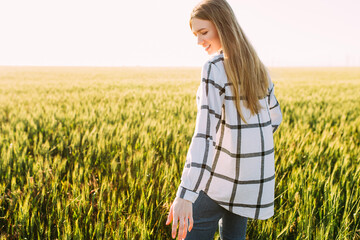 woman in a wheat field against the background of the sunset