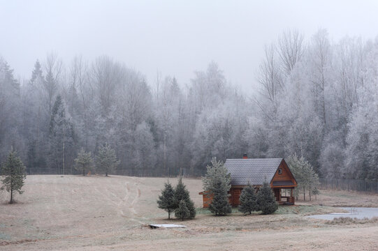A house on the edge of the forest next to the pond. Surrounded by frosted trees in complete silence of the estate.