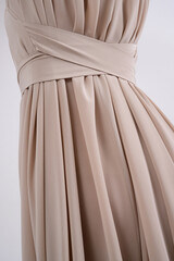 Beautiful beige pleated dress on girl's body. Fashionable feminine clothes. Back view. Wedding dress tailoring. Closeup.