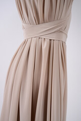 Beautiful beige pleated dress on girl's body. Fashionable feminine clothes. Back view. Wedding dress tailoring.