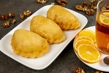 Fresh aromatic pastries for breakfast or snack on a square white plate, 
a cup of tea with lemon