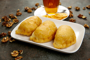 Fresh aromatic pastries for breakfast or snack on a square white plate, 
a cup of tea with lemon