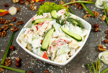 Fresh vegetable salad with mayonnaise in a square white plate. On a gray concrete textured background