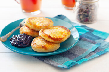 Naklejka na ściany i meble Cheese pancakes on blue plate with tea and jam
