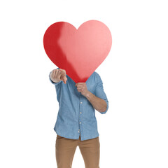 young casual guy covering face with big red heart