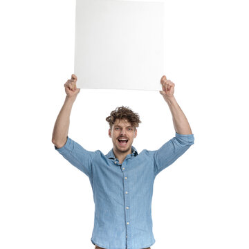happy young guy in denim shirt holding board above head