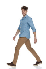 happy young casual guy smiling and walking to side