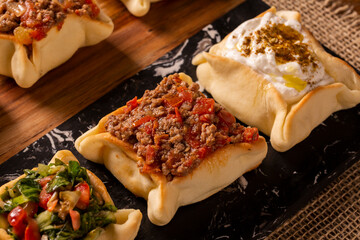 Varieties of Arabic sfihas open on rustic background. Meat, dry curd and endive.