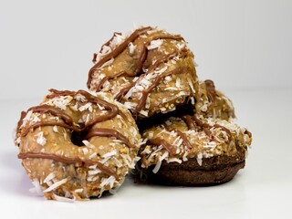 Pile of German Chocolate donuts / doughnuts, a chocolate base with German Chocolate frosting and a chocolate drizzle and shredded coconut!  Delicious baked goods ready to eat.