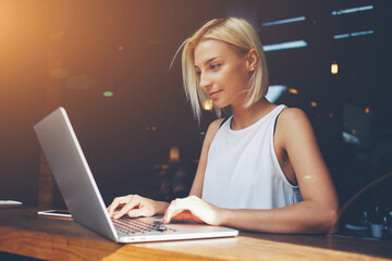 Charming happy woman student using laptop computer to prepare for the course work