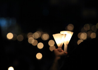 finding the light in dark. a haza candlelight vigil find each other in darkness, blur background in...