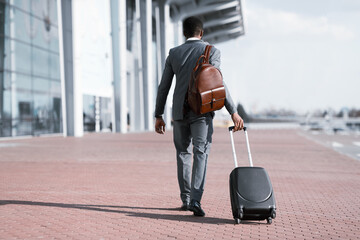 Businessman With Travel Suitcase Walking Back To Camera Leaving Airport