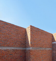 Vertical image of red brick wall under construction site with blue sky in day time
