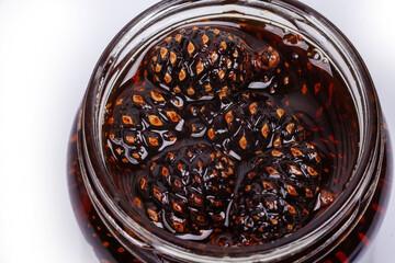 Pine cone jam in a glass jar, close-up on a white background