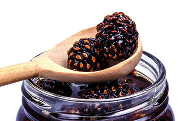 Pine cone jam in a glass jar, close-up on a white background, isolated