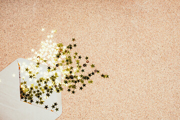 Gift envelope with confetti stars on suberic background. Festive holiday background. Celebration concept. Top view, flat lay.