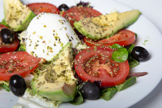 Mozzarella salad with avocado tomatoes and black olives. Isolated image. Selective focus.