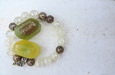   two colored marmalade candies and a bead bracelet on a wooden white surface, copy space , flat...
