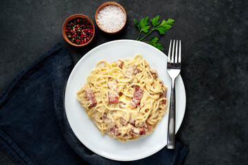 Homemade carbonara pasta in a white plate on a stone background