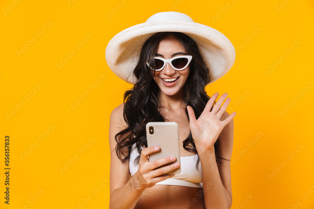 Wall mural image of elegant cheerful woman waving hand and using cellphone