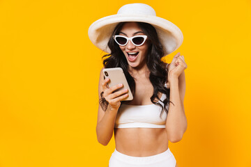 Image of amazed woman making winner gesture and using cellphone