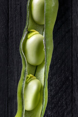 Fresh picked broad beans on a wooden table.