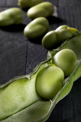 Fresh picked broad beans on a wooden table.