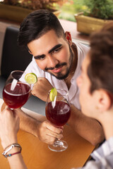 Gay couple flirting with their beloved in restaurant with glasses of wine