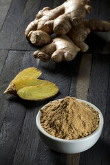 Ground ginger root in a bowl on a wooden table.