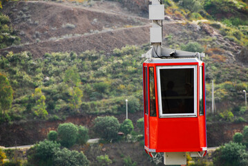 Red cable car that passes over the city of Zacatecas Mexico on the Cerro de la Bufa, with a green...