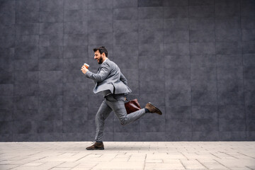 Young attractive bearded businessman running to work.