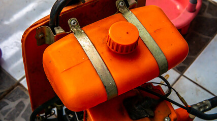 Close up of orange brush cutter machine on the floor. Lawn mower grass trimmer machine body detail.