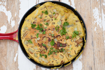 A Libyan potato omelette in a pan with fresh parsley