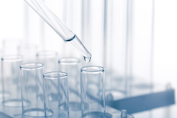pipette with a drop and scientific laboratory test tubes in a research laboratory.