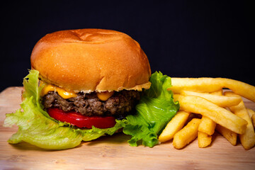 Burger on top of wooden tray with french fries 