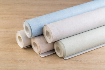 rolls of multi-colored paper wallpaper on a wooden table