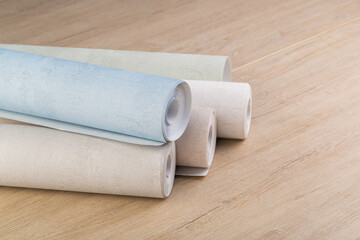 rolls of multi-colored paper wallpaper on a wooden table