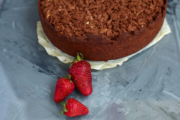 Chocolate cake is decorated with strawberry berries. Homemade cake. Pie on a grey background