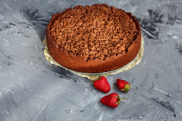 Chocolate cake is decorated with strawberry berries. Homemade cake. Pie on a grey background