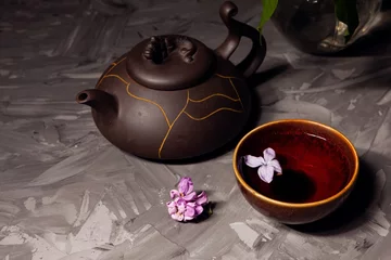 Foto op Aluminium Chinese tea. Tea bowl and teapot on a dark background. Lilac flower floating in tea © Мария Чичина