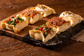 Varieties of Arabic sfihas open on rustic background. Meat, dry curd and endive.