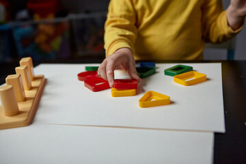 The boy is playing in his room. Educational game. Learning shapes and colors. A child plays with a sorter.