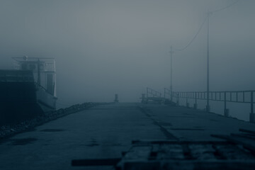 gloomy foggy pier by the lake. mystical fog on the pier.