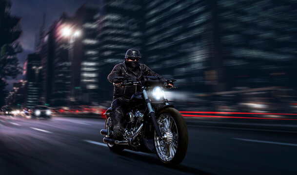 biker in black leather fast riding chopper motorcycle while being chased by car downtown at night