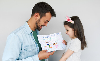Cute little daughter giving the greeting card making by herself for her awesome father on holiday for Father's day. Loving daddy and his little girl enjoying time together. Fatherhood concept.