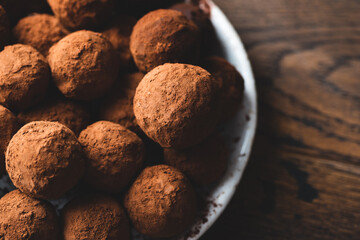 Homemade dark chocolate truffles on wooden background. Heap of cocoa covered chocolate truffles