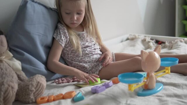 A little girl plays a developmental game that helps to learn the numbers and composition of the number.
