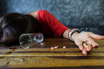 Woman taking medicine overdose and lying on the wooden table, overdose and suicide concept